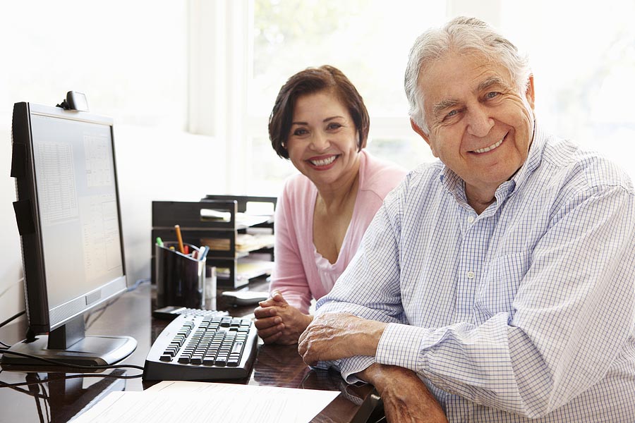 Senior Hispanic professional couple working on computer at home